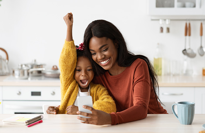 mother and daughter smiling looking at a phone